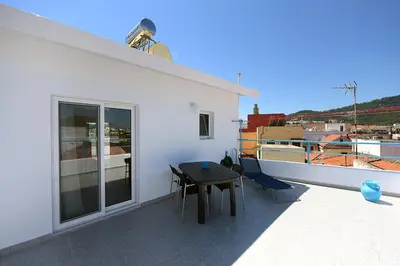a balcony with a table and a boat at Happy Days Home Apartment und Studio/Penthouse in Ialyssos