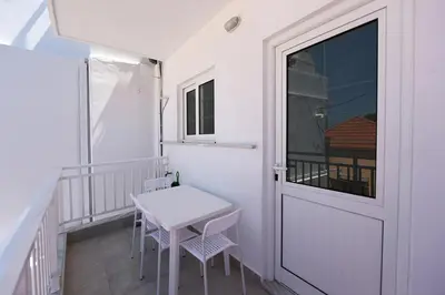 a small balcony with a table and a door at Happy Days Home Apartment und Studio/Penthouse in Ialyssos