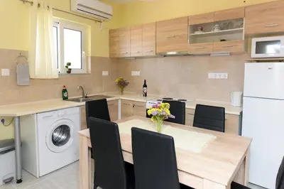a kitchen with a table with chairs and a refrigerator at Happy Days Home Apartment und Studio/Penthouse in Ialyssos
