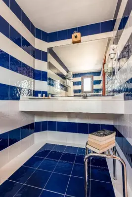 a blue tiled bathroom with a stool and a mirror at Villa Lindos Muse in Líndos