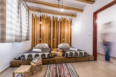 a bedroom with two beds and a wooden wall at Villa Lindos Muse in Líndos