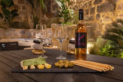 a bottle of wine and two wine glasses on a table at Casa Della vita Suite ,Old Town Rhodes in Rhodes Town