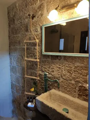 a stone bathroom with a sink and a mirror at Porolithos Boutique Hotel in Rhodes Town