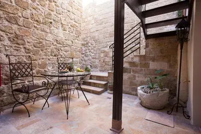 a patio with a table and a stone wall at Porolithos Boutique Hotel in Rhodes Town