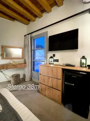 a living room with a large television and a dresser at Lindos Serenity Suites in Líndos