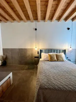 a bedroom with a large bed in a room with wooden ceilings at Lindos Serenity Suites in Líndos
