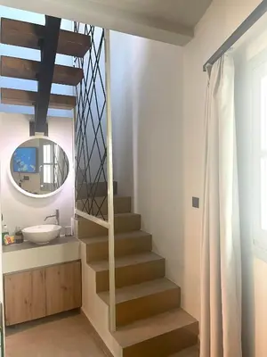 a bathroom with a staircase with a sink and a mirror at Lindos Serenity Suites in Líndos