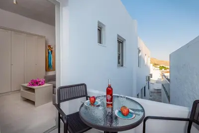 a glass table with two bottles and fruit on a balcony at Lindos orchid villa in Líndos