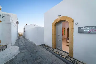 an alley with a white building with a door at Lindos orchid villa in Líndos