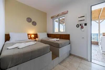 two beds in a room with a window at Aperanto Galazio Apartment in Archangelos