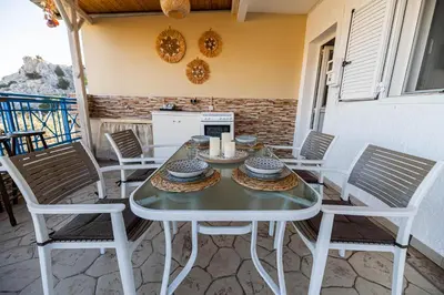a white table and chairs on a patio at Aperanto Galazio Apartment in Archangelos