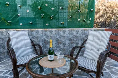 two chairs and a glass table with a bottle of wine at Aperanto Galazio Apartment in Archangelos