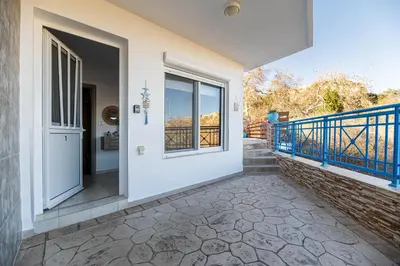 a house with a balcony and a door at Aperanto Galazio Apartment in Archangelos