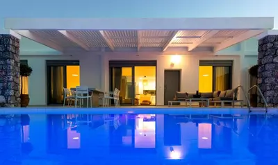 a large swimming pool with chairs and a living room at Villa Emerald with swimming pool in Lindos in Líndos