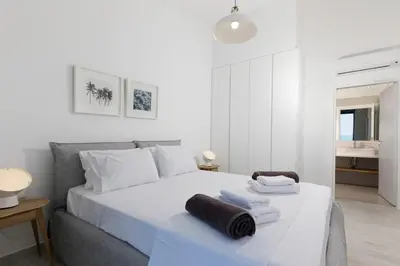 a white bedroom with a bed with towels on it at Villa Estella with pool & jacuzzi in Lindos in Líndos