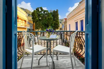 a patio with a table and chairs on a balcony at Ritzi Apartment in Symi