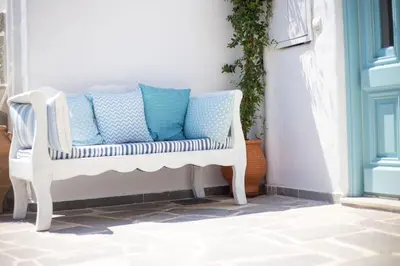 a white chair with blue pillows on a porch at White Rose in Kalithies