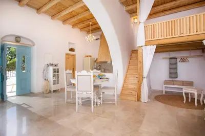 a large room with a table and a staircase at White Rose in Kalithies