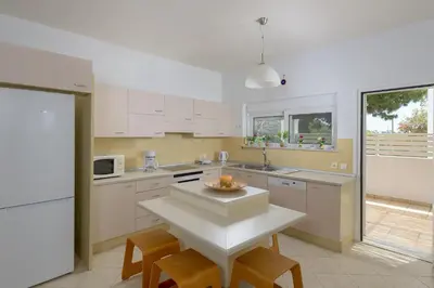 a kitchen with white cabinets and a table and chairs at Villa Evelyn in Pefki Rhodes