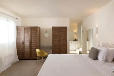 a bedroom with a large bed and a yellow chair at South Key Villa in Pefki Rhodes