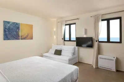 a white bedroom with a white bed and a couch at South Key Villa in Pefki Rhodes