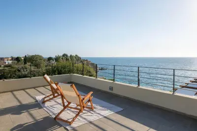 a pair of chairs sitting on a balcony overlooking the ocean at South Key Villa in Pefki Rhodes