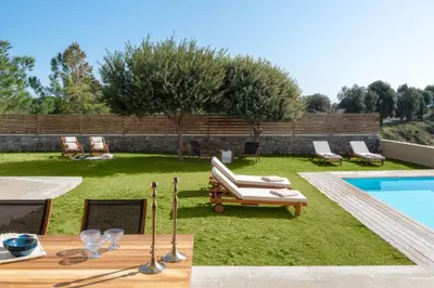 a backyard with a swimming pool and a lawn with chairs at South Key Villa in Pefki Rhodes