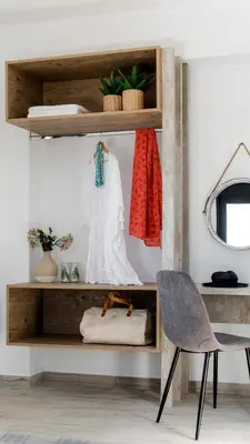 a wooden shelf with a dress and a chair at Kiotari Akti Beachfront Villas in Gennadi