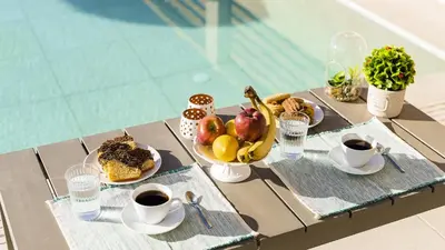 a table with a plate of food and cups of coffee at Kiotari Akti Beachfront Villas in Gennadi