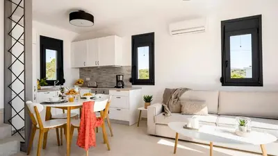a kitchen and living room with a table and a couch at Kiotari Akti Beachfront Villas in Gennadi