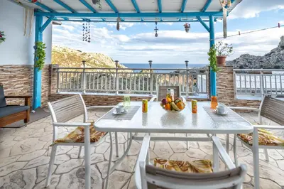 a table and chairs on a patio with a view of the ocean at Springs Petronas Apartment in Archangelos