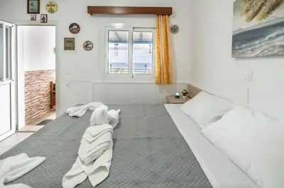 a bedroom with a white bed with a dog laying on it at Springs Petronas Apartment in Archangelos