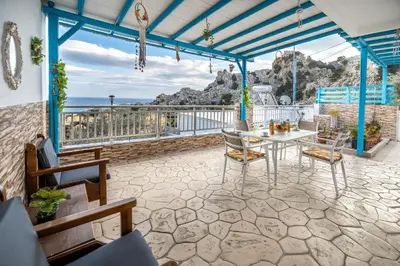 a patio with a table and chairs and the ocean at Springs Petronas Apartment in Archangelos