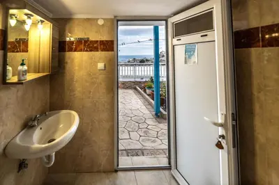 a bathroom with a sink and a sliding glass door at Springs Petronas Apartment in Archangelos
