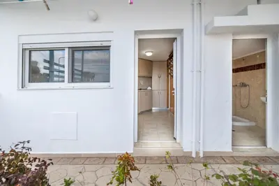 a white house with a window and a bathroom at Springs Petronas Apartment in Archangelos