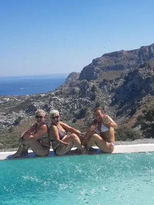 a group of women sitting on the edge of a swimming pool at Bouganville Bed & Breakfast Stegna in Archangelos