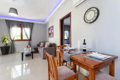 a dining room and living room with a table and a clock at Garden house in Kremasti