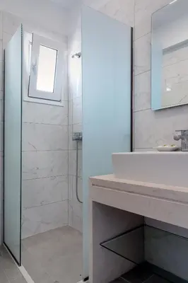 a bathroom with a shower and a sink and a mirror at Aegean Horizon apartments in Gennadi