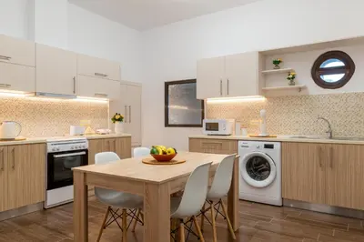 a kitchen with a wooden table and white cabinets at Kolymbia memories house in Kolimbia