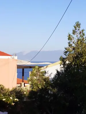 a view of a building with trees in the foreground at Stone House Halki in Halki
