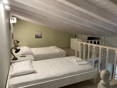 two white beds in a room with at Stone House Halki in Halki