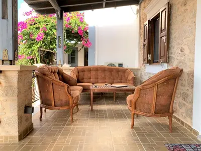 a patio with two wicker chairs and a couch at Stone House Halki in Halki