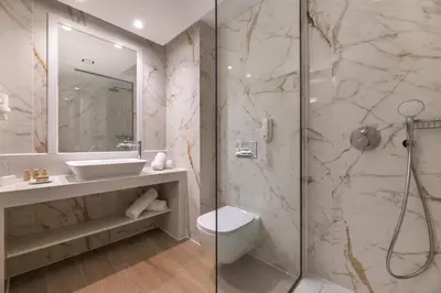 a bathroom with a shower and a sink and a toilet at Acandia Hotel in Rhodes Town