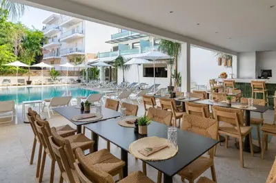 a restaurant with tables and chairs next to a swimming pool at Acandia Hotel in Rhodes Town