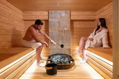 a man and woman sitting in a sauna at Acandia Hotel in Rhodes Town