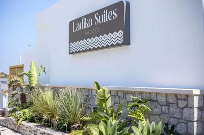 a sign for a hotel with plants on a wall at Ladiko Suites - Faliraki in Faliraki