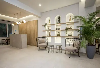 a lobby with two chairs and shelves with plants at Ladiko Suites - Faliraki in Faliraki