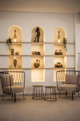 a room with two chairs and tables and shelves with vases at Ladiko Suites - Faliraki in Faliraki