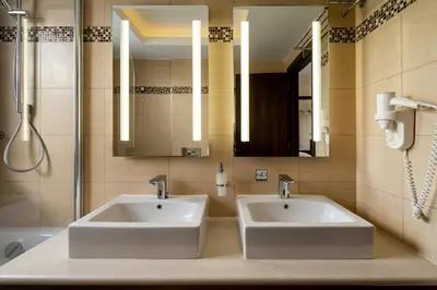 two sinks in a bathroom with two mirrors at Ladiko Suites - Faliraki in Faliraki