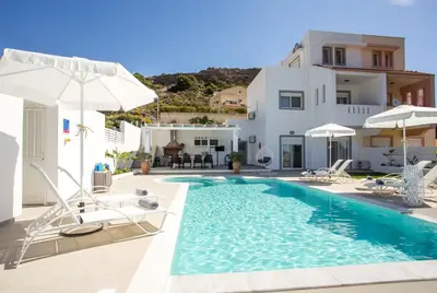 a villa with a swimming pool with chairs and umbrellas at La Casa Del Amor in Kalithies